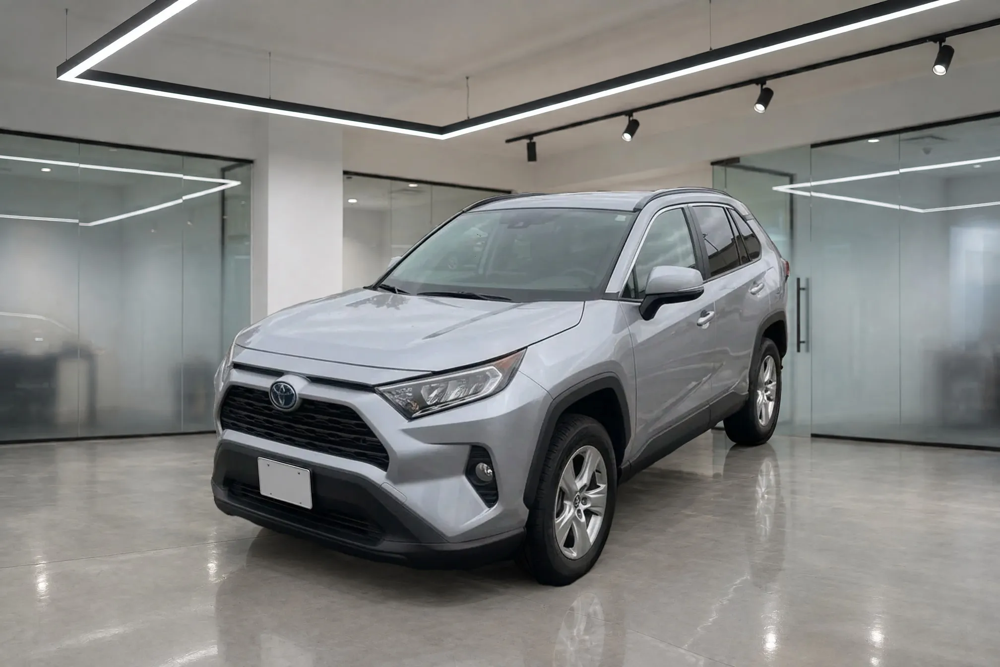 The same silver Toyota RAV4 standing in a bright Showroom with glass walls and a polished concrete floor